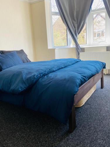 un letto blu in una camera da letto con finestra di Instant Lodge a Leicester