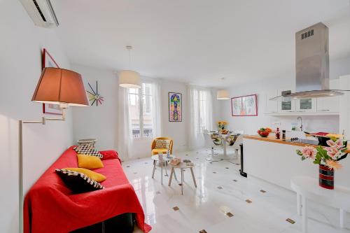 a living room with a red couch and a kitchen at Appartement Picasso - Old Town Antibes - Happy Rentals in Antibes