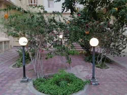 two lights in a courtyard with trees and flowers at Nizwa Hotel Apartments in Nizwa