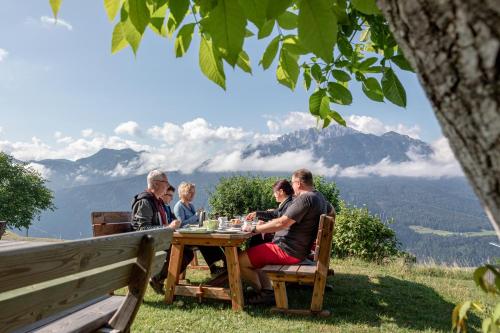 a group of people sitting around a wooden table at Mösslacher's Ferienwohnungen in Hermagor