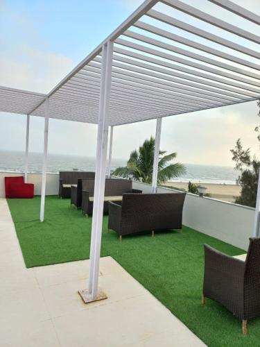 une pergola avec des tables et des chaises sur une terrasse donnant sur la plage dans l'établissement ELITE MANDARMONI, à Mandarmoni