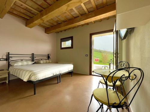 Schlafzimmer mit einem Bett, einem Tisch und einem Fenster in der Unterkunft Casale dei Cinque Colli in Ostra