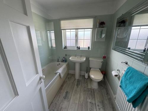 een badkamer met een wastafel, een toilet en een bad bij Central City Centre 3 bedroom home Private Parking in Plymouth
