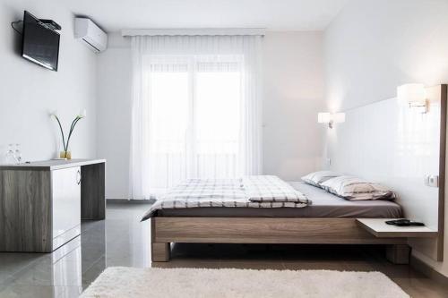 um quarto branco com uma cama e uma televisão em Hotel Rođo em Teslic