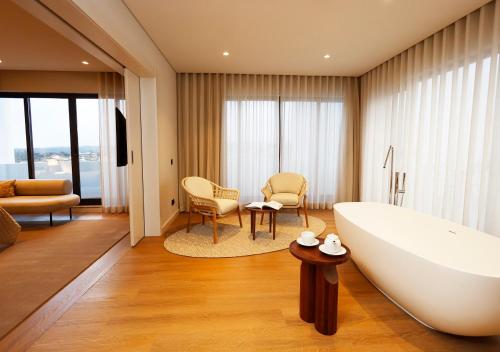 a bathroom with a large tub and a living room at Montebelo Viseu Congress Hotel & Spa in Viseu