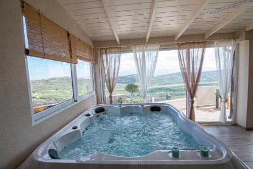 a bath tub in a room with a large window at Nikola's endless view in Stíronas