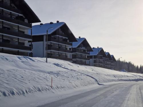 a snow covered road in front of a building at Tahko Apartment Kehtola, Tahkovuori in Tahkovuori