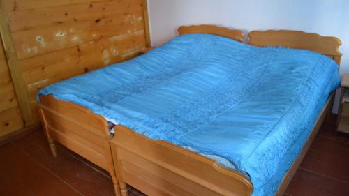 uma cama de madeira com um cobertor azul em Tasty house Zebo with canyon view em K'eda