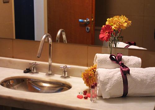 a bathroom sink with towels and a vase of flowers at Hotel El Cortijo in Neuquén