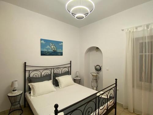 una camera da letto con un letto con lenzuola bianche e una lampada di Villa Jenny Stylianou a Spetses