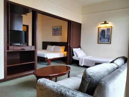 um quarto de hotel com um sofá e uma cama e uma televisão em Plaza Suite At Times Square Kuala Lumpur em Kuala Lumpur
