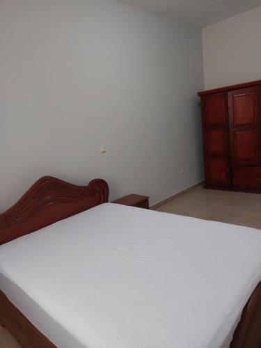 1 dormitorio con cama blanca y tocador de madera en Résidence beau-lieu, en Awaé I