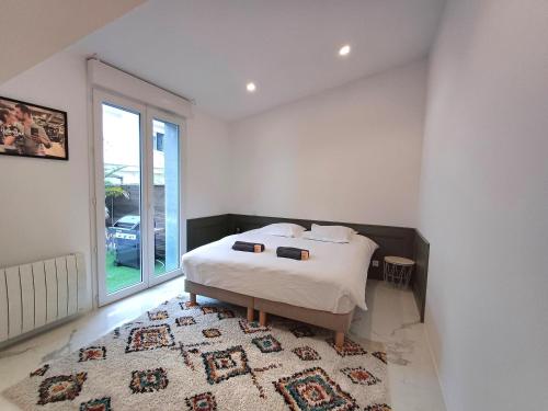 a white bedroom with a bed and a rug at Ranndi Terras - Yourhosthelper conciergerie in Lanester