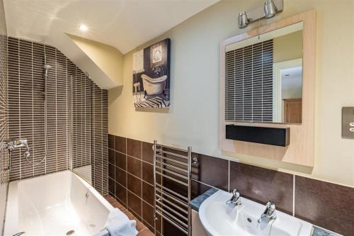 een badkamer met een bad, een wastafel en een spiegel bij The Brantwood Hotel in Penrith