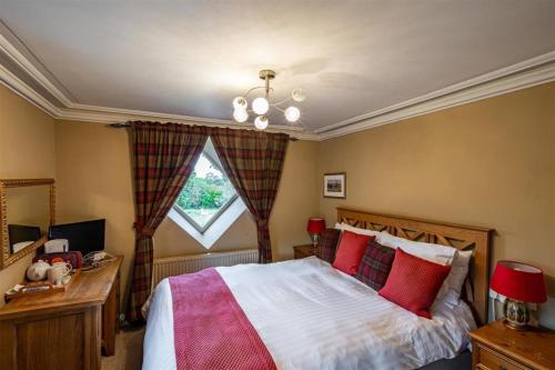 a bedroom with a bed with red pillows and a window at The Brantwood Hotel in Penrith