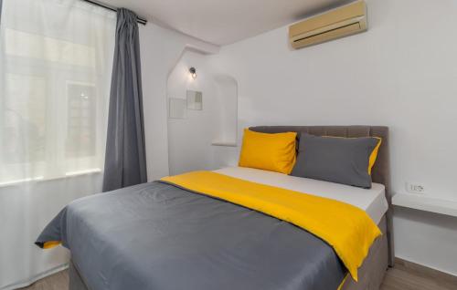 Rab Stari grad في راب: سرير مع وسائد صفراء ورمادية ونافذة