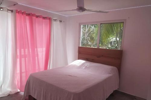 um quarto com uma cama e uma janela com cortinas cor-de-rosa em Villa vue sur Océan em Las Terrenas