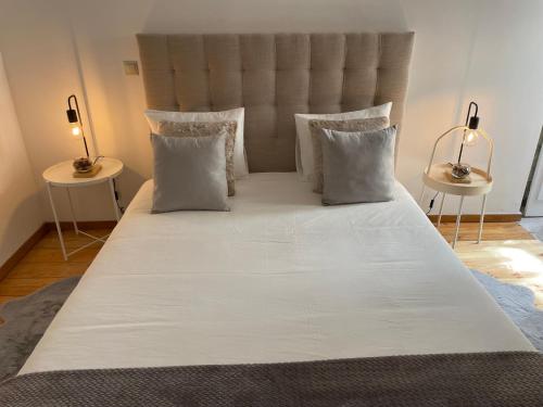 ein großes Bett mit weißer Bettwäsche und Kissen in der Unterkunft Douro River Charming Flats in Porto