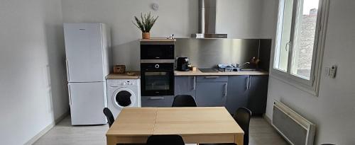 une petite cuisine avec une table et un réfrigérateur dans l'établissement Appartement à proximité de toutes commodités, à Rivesaltes