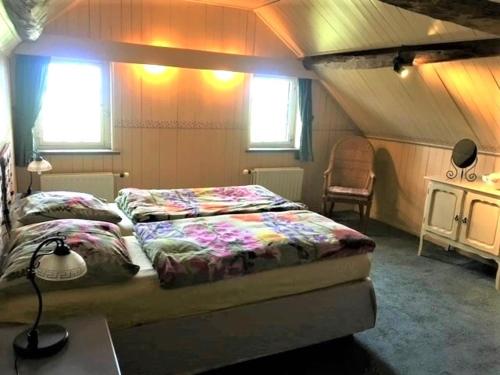 a bedroom with a bed and a desk and two windows at Droomboerderijtje in Merselo
