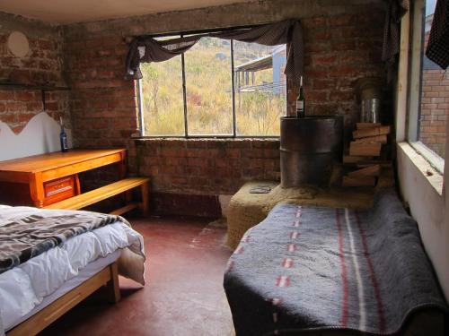 um quarto com uma cama, uma mesa e uma janela em Andean Mountains Hostel em Huaraz