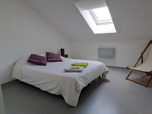 1 dormitorio con 1 cama blanca grande con almohadas moradas en Appartement proche centre ville et sur les remparts, en Langres