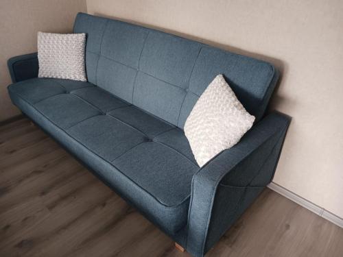 eine blaue Couch mit zwei Kissen an der Wand in der Unterkunft Kandavas Apartments in Daugavpils