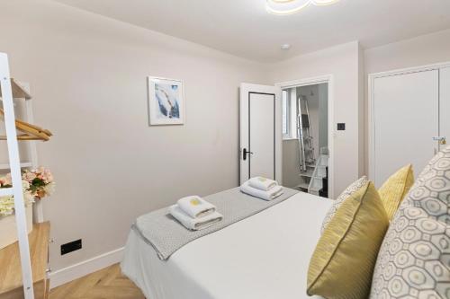 a white bedroom with a bed with towels on it at Stunning 2-Bed Apartment Fully Equipped - Clapham Junction - Battersea - 5 Minutes Train Station in London