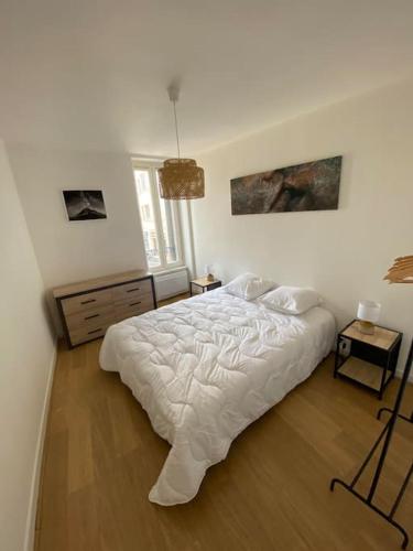 une chambre avec un lit blanc et un parquet dans l'établissement Appartement Centre Salins 4 pers, à Clermont-Ferrand