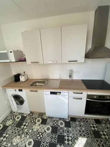 - une cuisine avec des placards blancs et un sol noir et blanc dans l'établissement Appartement Centre Salins 4 pers, à Clermont-Ferrand