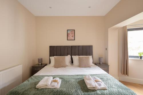 Morden的住宿－Charming Two-Bedroom Retreat in Morden SM4, London，一间卧室配有一张床,上面有两条毛巾