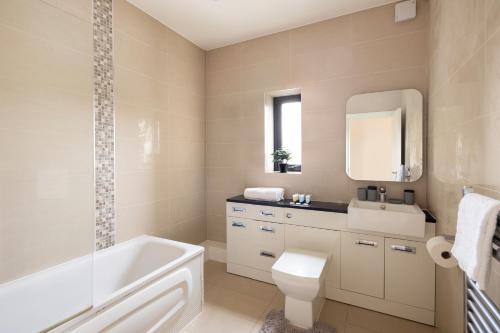 La salle de bains est pourvue d'une baignoire, de toilettes et d'un lavabo. dans l'établissement Charming Two-Bedroom Retreat in Morden SM4, London, à Morden