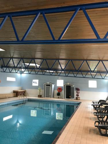a large swimming pool with chairs in a building at Brixham Holiday Park Gold 2 Bedroom Holiday Home in Brixham