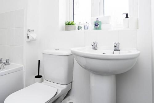 La salle de bains blanche est pourvue de toilettes et d'un lavabo. dans l'établissement K Suites - Shetland Court, à Bridgwater
