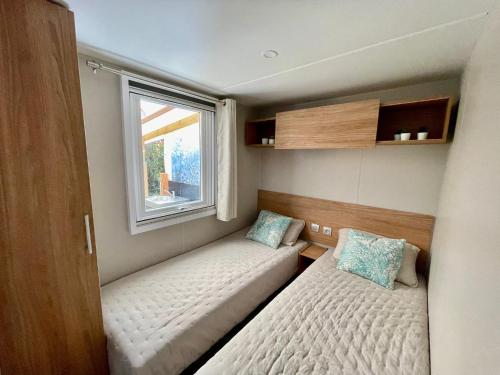 um pequeno quarto com 2 camas e uma janela em Mobil-home golfe de Saint Tropez em Gassin