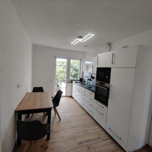 eine Küche mit einem Tisch und einem weißen Kühlschrank in der Unterkunft City Apartments Offenbach in Offenbach