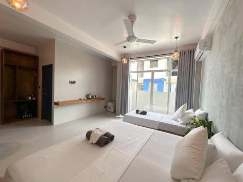 1 dormitorio con cama blanca y ventana grande en The Palm Ray Rasdhoo, en Rasdu