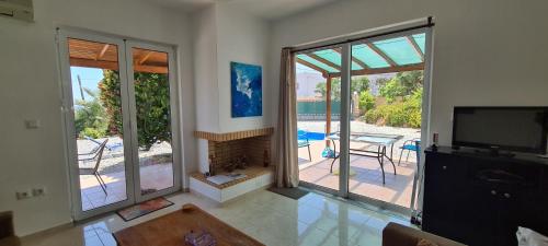 a living room with a fireplace and sliding glass doors at Villa Nisi in Agia Galini