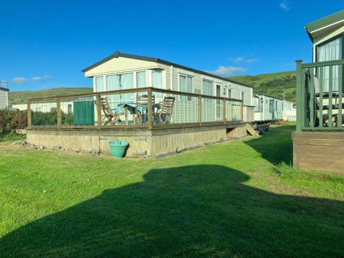 a house with a large deck in a yard at Cosy caravan Sunbeach in Llwyngwril