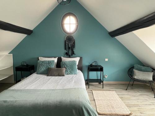 une chambre avec un grand lit avec un mur bleu dans l'établissement Maison de Caractère, à Villers-sous-Saint-Leu