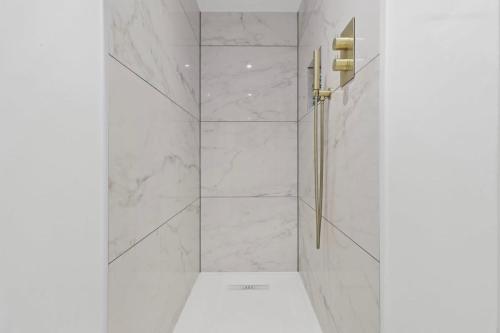 a bathroom with a shower with white marble walls at Seaside Serenity Modern Apartment Close To Beach in Eastbourne