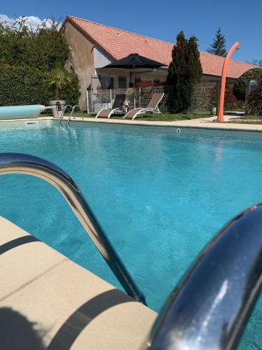 a swimming pool with blue water in front of a house at Hôtel Le Clos Badan in Nuits-Saint-Georges