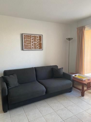 a living room with a blue couch and a table at APPART - T3 - 6 PERSONNES – GOLF CAP D’AGDE in Cap d'Agde