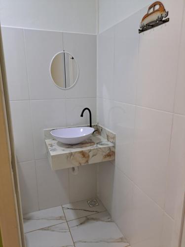 a white bathroom with a sink and a mirror at Girassol Hostel by Katita in Paraty