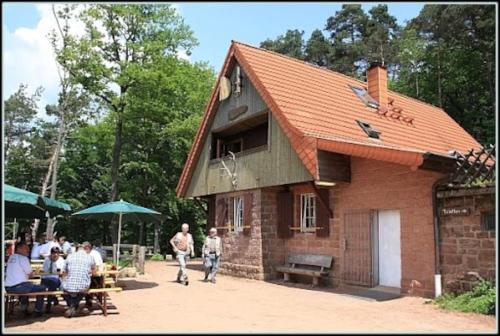 ein kleines Backsteingebäude mit Leuten, die davor laufen in der Unterkunft Ferienwohnung Jungpfalzstieg in Rinnthal