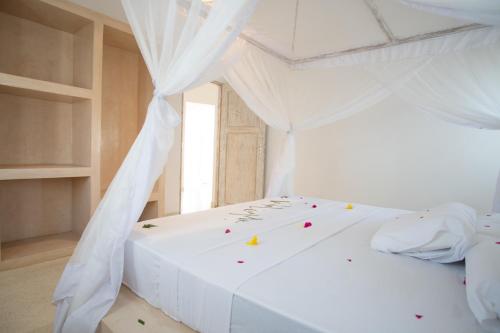 a bedroom with a white bed with a canopy at Rafiki Tamu Residential Resort in Watamu