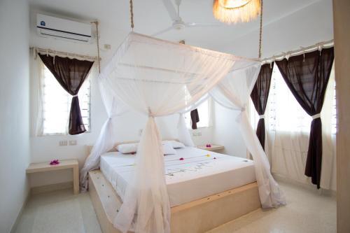 a bedroom with a bed with a mosquito net at Rafiki Tamu Residential Resort in Watamu