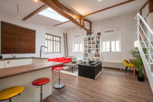 - une cuisine et un salon avec des tabourets rouges et jaunes dans l'établissement Magnifique loft avec extérieur, à Paris