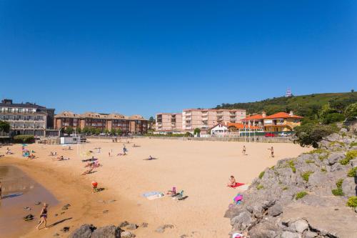 a group of people on a beach with buildings at Apartamentos Astuy in Isla