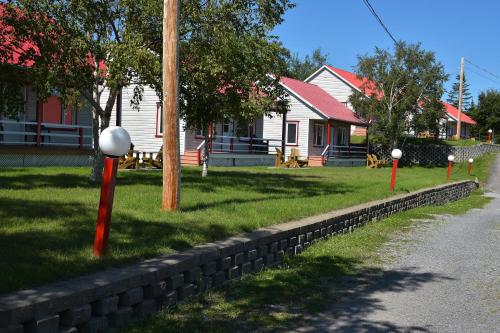 a house with red poles in the grass next to a street at Motel et Chalets Bo-Fleuve Evangeline in Saint-Siméon